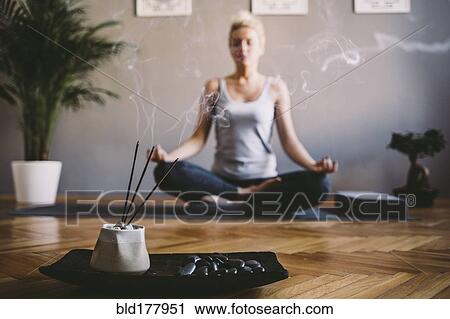 Stock Image - Caucasian woman meditating in yoga studio. Fotosearch