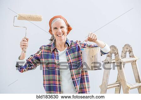 Stock Image - Caucasian woman painting in new home. Fotosearch