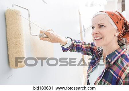 Stock Image - Caucasian woman painting in new home. Fotosearch