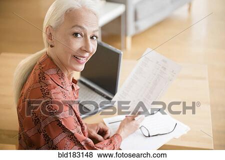 Stock Photo - Caucasian woman paying bills on laptop. Fotosearch