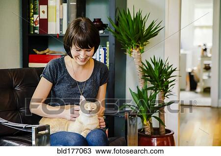 Caucasian woman petting cat in living room View Large Photo Image Stock Image - Caucasian woman petting cat in living room. Fotosearch