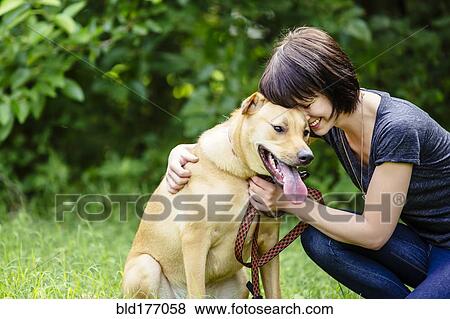 Stock Photo - Caucasian woman petting dog in field. Fotosearch