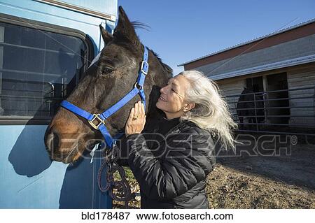 Stock Photo - Caucasian woman petting horse on ranch. Fotosearch