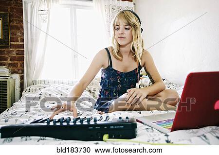 Caucasian woman playing keyboard on bed View Large Photo Image Stock Image - Caucasian woman playing keyboard on bed. Fotosearch