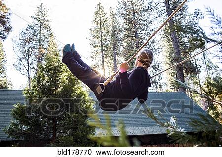 Stock Image - Caucasian woman playing on swing. Fotosearch