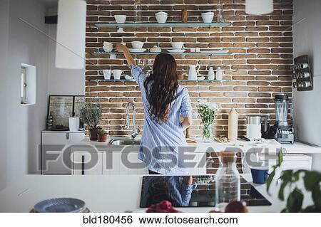 Caucasian woman reaching for dishes in kitchen View Large Photo Image Stock Photograph - Caucasian woman reaching for dishes in kitchen. Fotosearch