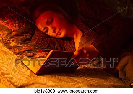 Stock Photo - Caucasian woman reading book in bed. Fotosearch