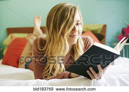 Stock Photo - Caucasian woman reading book on bed. Fotosearch