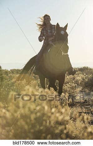 Caucasian woman riding horse on dirt path View Large Photo Image Stock Image - Caucasian woman riding horse on dirt path. Fotosearch