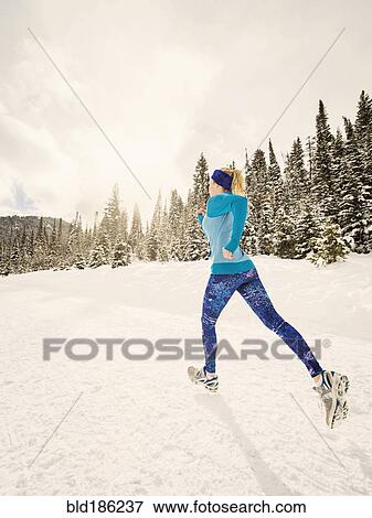 Stock Photo - Caucasian woman running in snowy landscape. Fotosearch