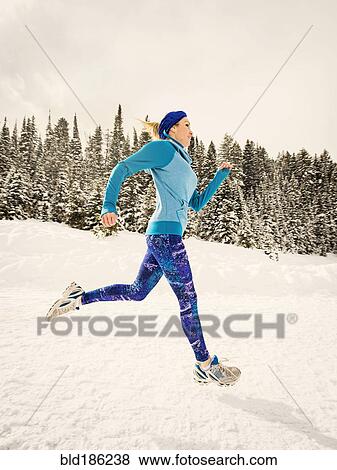 Stock Photo - Caucasian woman running in snowy landscape. Fotosearch