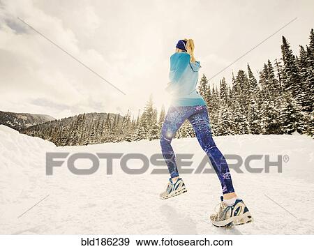 Stock Photo - Caucasian woman running in snowy landscape. Fotosearch