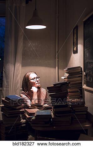 Stock Photo - Caucasian woman sitting at stack of books. Fotosearch