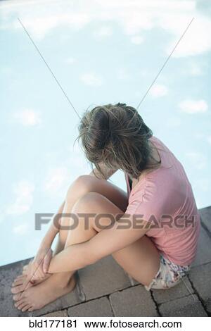 Stock Image - Caucasian woman sitting at swimming pool. Fotosearch