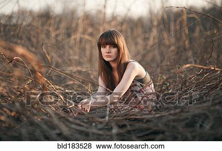 Caucasian woman sitting in field View Large Photo Image Stock Photo - Caucasian woman sitting in field. Fotosearch