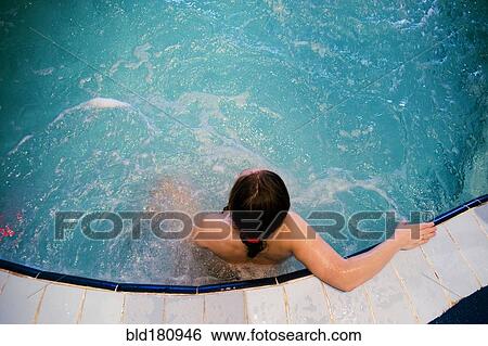 Stock Photograph - Caucasian woman sitting in swimming pool. Fotosearch