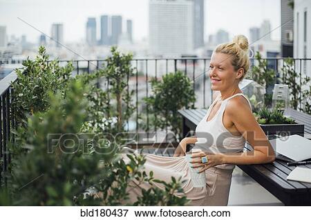 Stock Photo - Caucasian woman sitting on balcony. Fotosearch