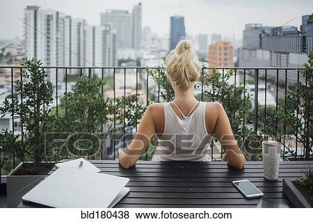 Stock Photo - Caucasian woman sitting on balcony. Fotosearch