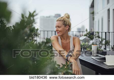 Stock Photograph - Caucasian woman sitting on balcony. Fotosearch