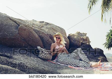 Stock Image - Caucasian woman sitting on beach. Fotosearch