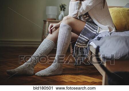 Stock Image - Caucasian woman sitting on bed. Fotosearch