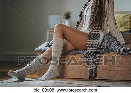 Stock Photo - Caucasian woman sitting on bed. Fotosearch