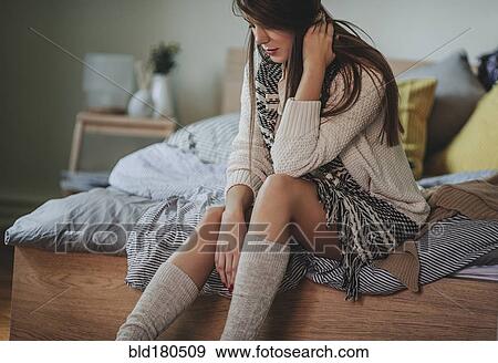 Stock Photo - Caucasian woman sitting on bed. Fotosearch