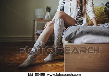 Stock Photo - Caucasian woman sitting on bed wearing socks. Fotosearch