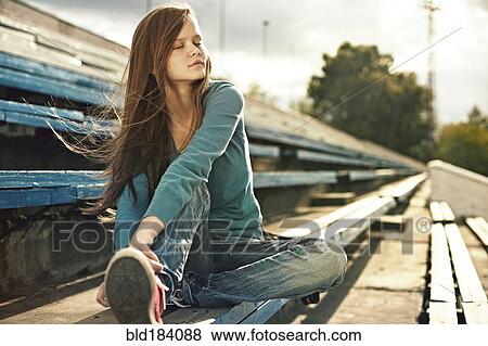 Stock Photo - Caucasian woman sitting on bleachers. Fotosearch