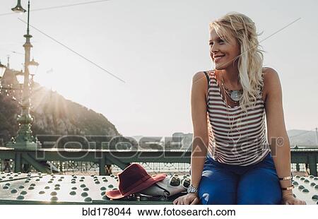 Picture - Caucasian woman sitting on bridge. Fotosearch