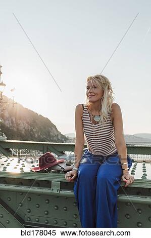 Caucasian woman sitting on bridge View Large Photo Image Stock Photography - Caucasian woman sitting on bridge. Fotosearch