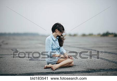 Stock Image - Caucasian woman sitting on concrete. Fotosearch