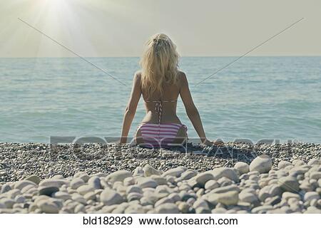 Caucasian woman sitting on rocky beach View Large Photo Image Stock Photo - Caucasian woman sitting on rocky beach. Fotosearch