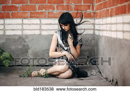 Stock Photo - Caucasian woman sitting on sidewalk with cats. Fotosearch