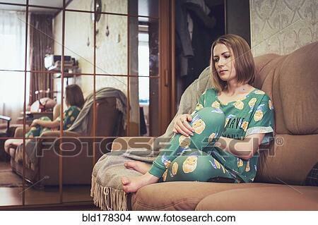 Picture - Caucasian woman sitting on sofa. Fotosearch