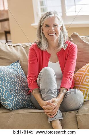 Stock Photography - Caucasian woman sitting on sofa. Fotosearch