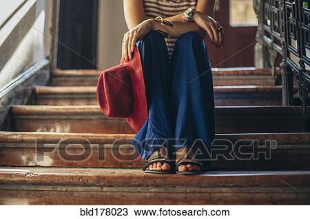 Stock Image - Caucasian woman sitting on stairs. Fotosearch