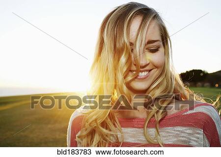Stock Image - Caucasian woman smiling in field. Fotosearch