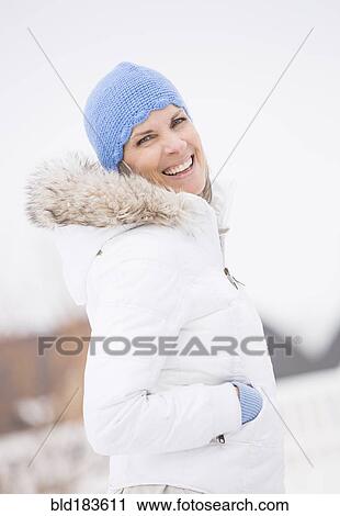 Stock Image - Caucasian woman smiling in snow. Fotosearch