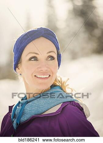 Stock Image - Caucasian woman smiling in snow. Fotosearch