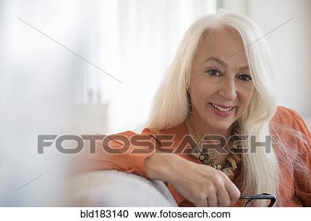 Stock Image - Caucasian woman smiling on sofa. Fotosearch