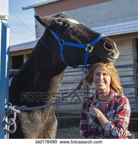 Stock Image - Caucasian woman smiling with horse on ranch. Fotosearch