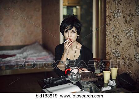 Stock Photo - Caucasian woman smoking cigarette in bedroom. Fotosearch