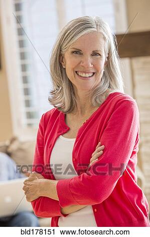 Stock Image - Caucasian woman standing in living room. Fotosearch