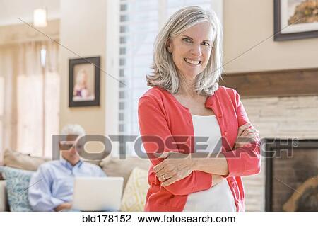 Stock Image - Caucasian woman standing in living room. Fotosearch