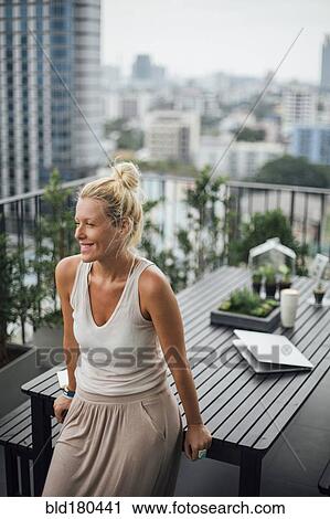Caucasian woman standing on balcony View Large Photo Image Stock Image - Caucasian woman standing on balcony. Fotosearch