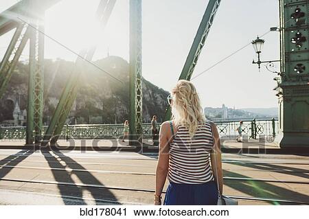 Stock Image - Caucasian woman standing on bridge. Fotosearch