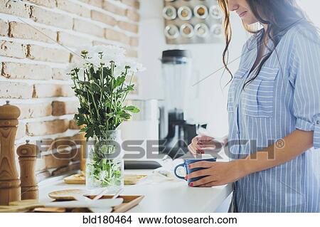 Picture - Caucasian woman stirring coffee in kitchen. Fotosearch