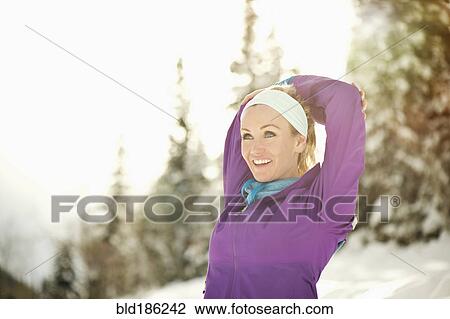 Stock Image - Caucasian woman stretching in snow. Fotosearch