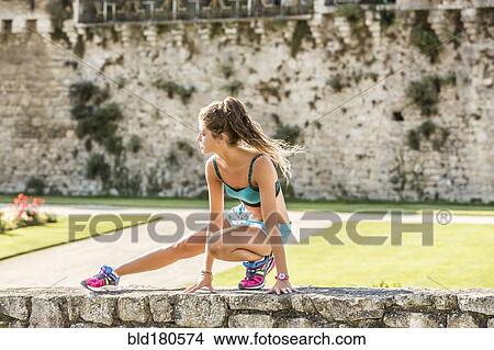 Picture - Caucasian woman stretching outdoors. Fotosearch